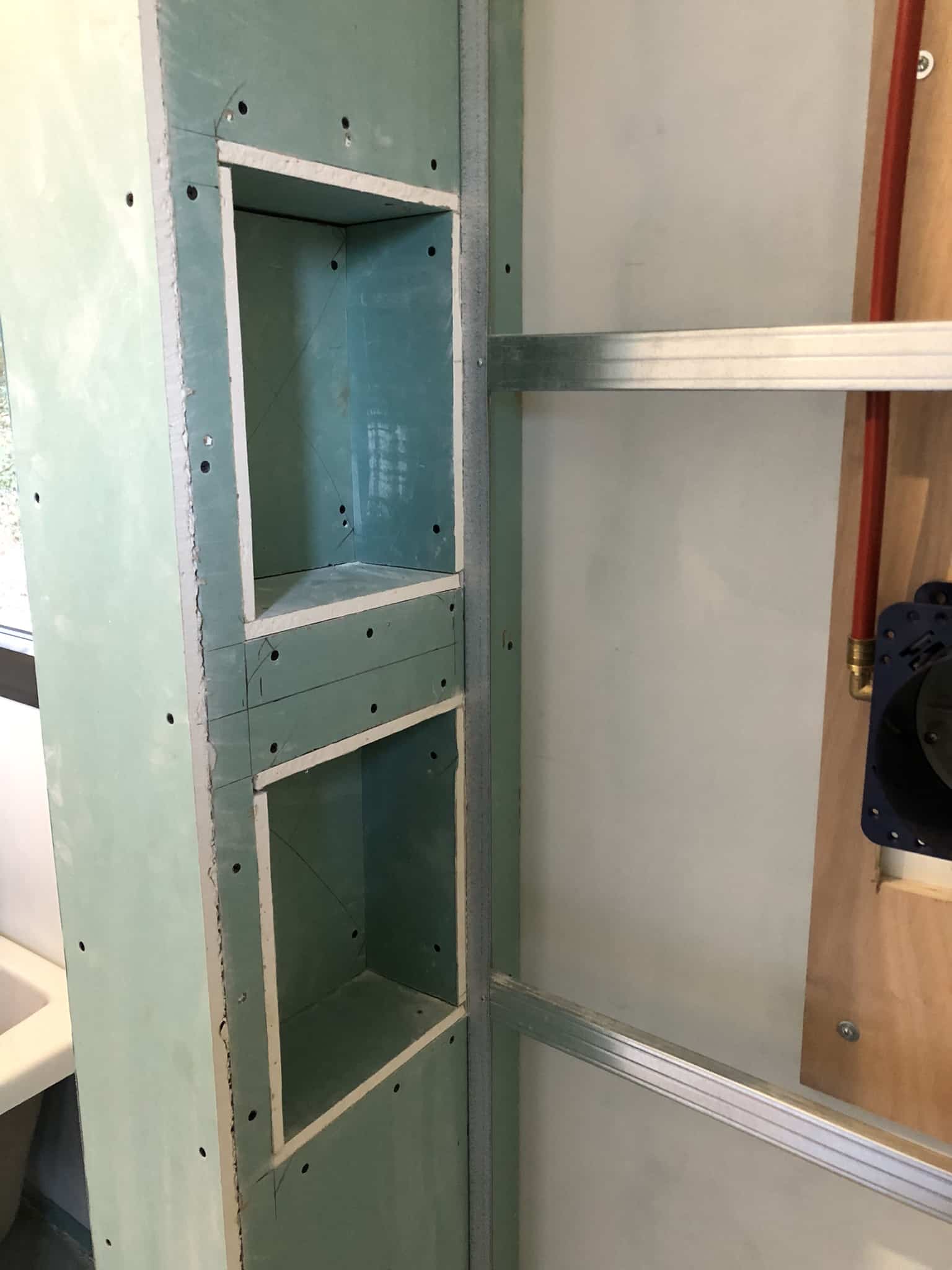 Niche de douche en placo : installation et rénovation Niches de douche encastrées dans du placo hydrofuge vert lors d'une rénovation de salle de bain avec ossature métallique.